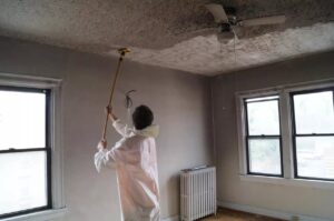 Technician in protective gear removing soot and smoke damage from a ceiling during fire damage restoration in Bellingham, WA