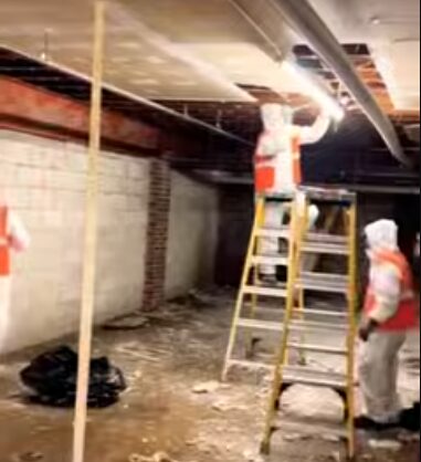 Restoration technicians repairing fire and water damaged ceiling in a commercial basement space in Bellingham, Washington.