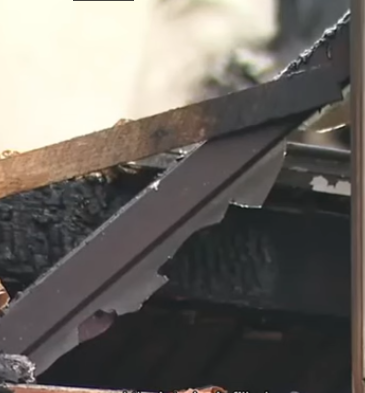 Close-up of a fire-damaged roof edge with charred shingles and framing in a Bellingham, Washington home.