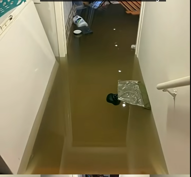 Flooded basement hallway with standing water in a Bellingham home after storm and flood damage.