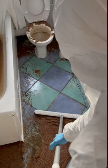 Technician repairing damaged flooring during sewage cleanup and restoration process