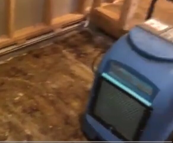 Sewage extraction machine placed on water-damaged flooring during cleanup process