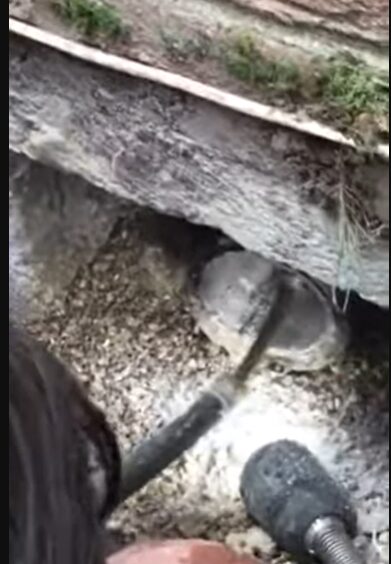 Technician repairing sewage line beneath property foundation during restoration work